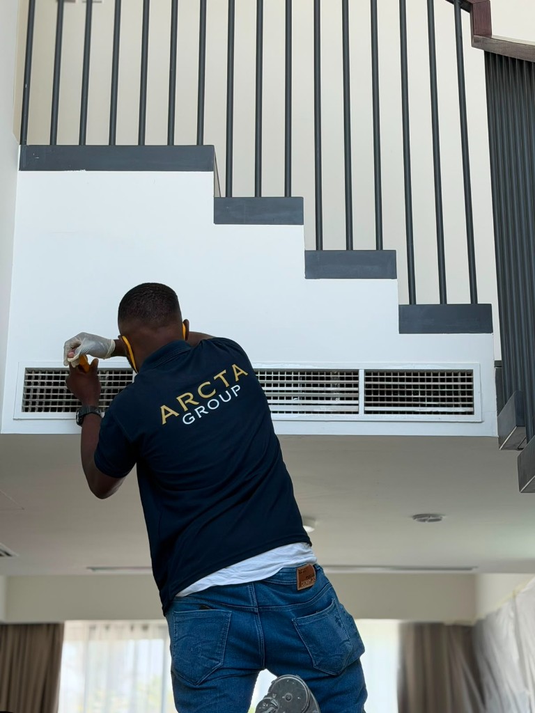 Arcta Group technician in branded uniform servicing an air conditioning vent in a premium Dubai home